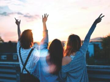 photo of three women lifting there hands