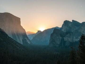 the sun is setting over a mountain range