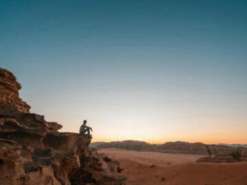 a man sitting on a rock in the desert