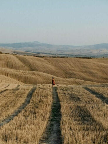 person in red jacket walking on brown field during daytime